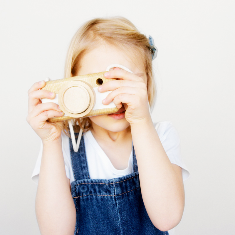 Kind hält Holzfotoapparat vor die Augen