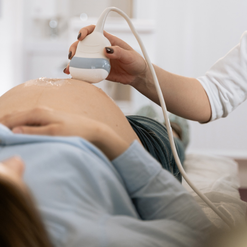 Ein Ultraschallgerät wird auf einen schwangeren Bauch gehalten